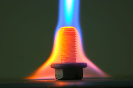 Heating a steel bolt with gas torch. Heating is part of a process of steel hardening.