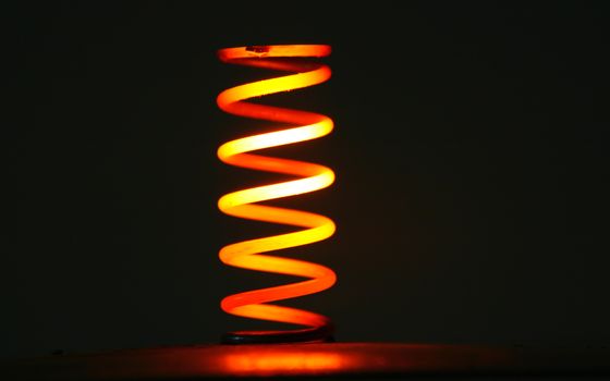 Red hot coil spring glowing in the dark.