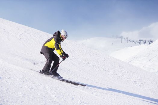 Alpine skier on piste running downhill in beautiful Alpine landscape. Blue sky on background. Free copy space for text