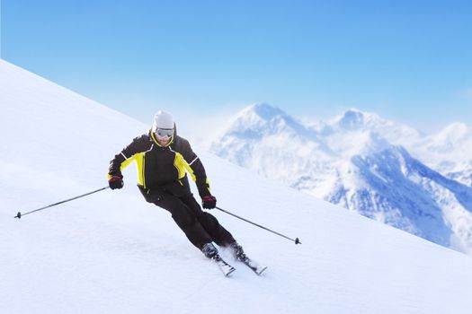 Alpine skier on piste running downhill in beautiful Alpine landscape. Blue sky on background. Free copy space for text