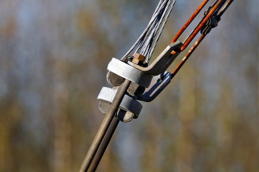 Old connection. Close photo of rusty tensioner of power lines. A threader rod connected to steele cables. Isolated from dark brown background