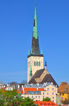 St. Olaf's church in Tallinn, Estonia. Sharp tower of the church with calm blue summer sky on the background. Some colorful buildings in the foreground.