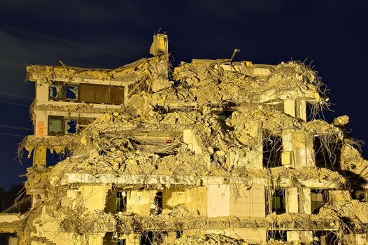 Collapsed large office building with interior rooms visible. Only rear wall still with broken windows standing.