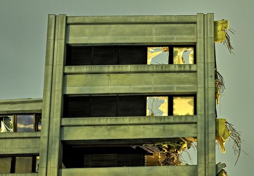 Only one wall of destroyed building still standing. Dramatic low light photo of a high wall with broken windows and cables hanging out.