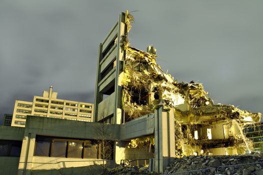 Only small part of a destroyed building still standing. Roof and most of the walls have collapsed. Dramatic night scene of a demolished concrete building.