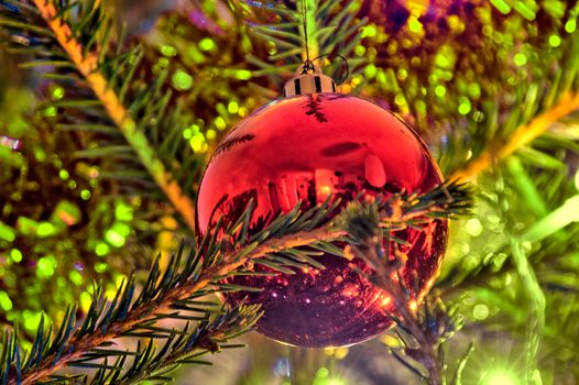 Large red ornament hanging on christmas tree.