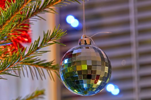 Beautiful sparkling disco ball on a green branch of christmas tree.