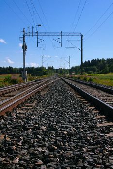 Empty railroad tracks and power lines hanging above.