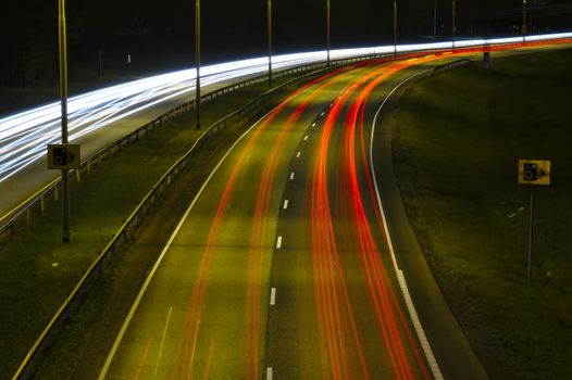 Night traffic on a highway. Passing cars leaving light trails