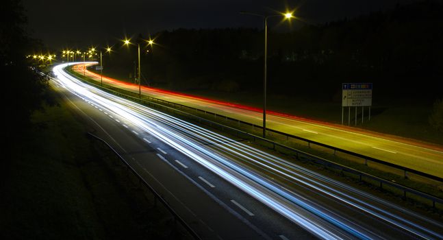 Fast traffic at night on busy motorway. Long exposure photo of cars leaving light trails.