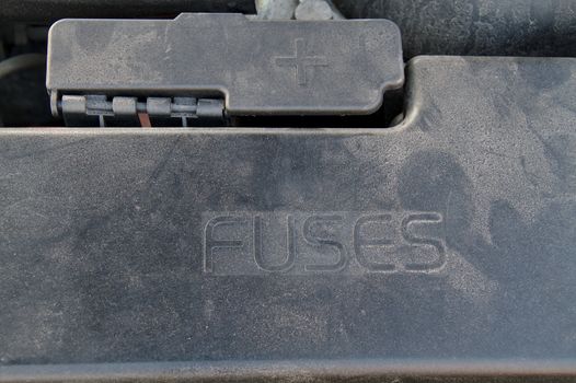 Cover of a under hood fuse box of a car. External plus terminal for jumper cables next to the fusebox.