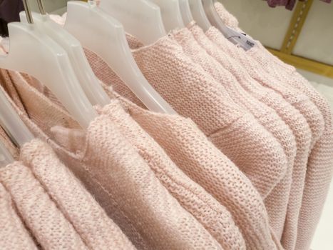 Knitted woolen sweaters on a hanger in the store.