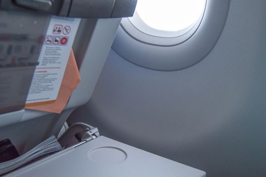 Folding table, flight instructions, magazine in the front seat, porthole, concept of flights and travel.