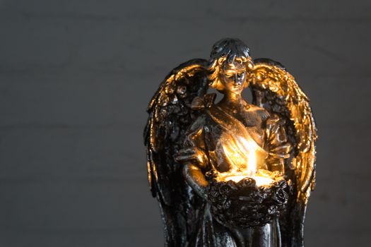 silver angel statue holding a burning candle in closeup, christmas and spiritual tradition