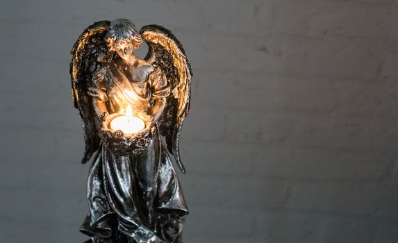 Christmas or spiritual tradition, a silver angel sculpture holding a burning light