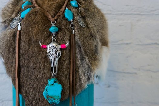 Native american background of animal fur decorated with a necklace with stones and a cow skull