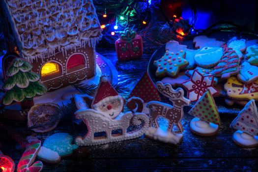 Gingerbread house and cookie figures with lights on dark background, xmas theme