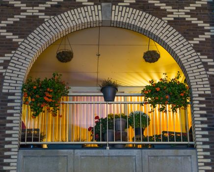 beautiful arched dutch balcony decorated with flowers at night, modern city buildings and architecture