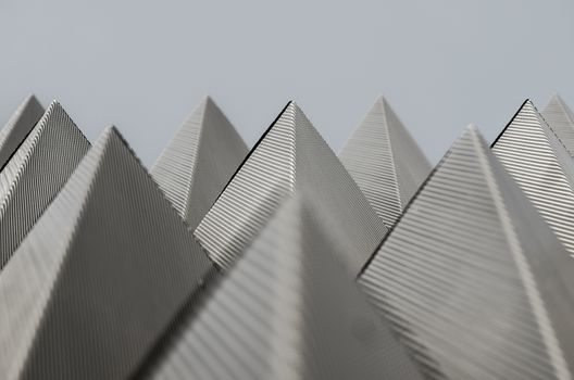 Symmetric piramidal pattern made of metallic planes with little holes in the Navarrabiomed building in Pamplona, Navarra, Spain