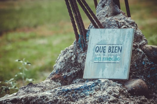 wooden piece with a beautiful message, standing on a big rock with metal spikes