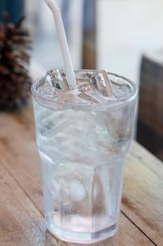 water in glass with ice  and drinking straw on table