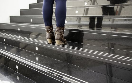 Women's boots on a staircase, fashion detail and present