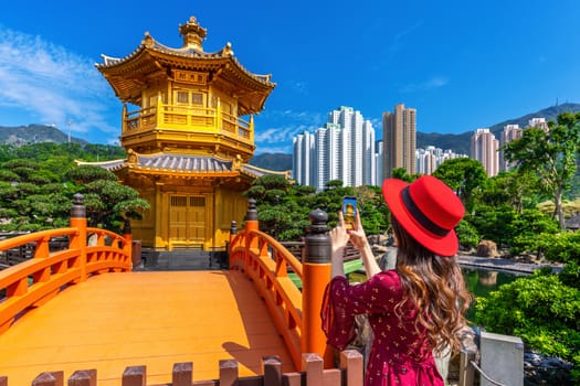 Woman take a photo at Golden Pavilion in Nan Lian Garden near Chi Lin Nunnery temple, Hong Kong.