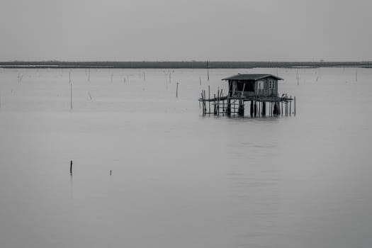 Black and white of fisherman house on ocean.