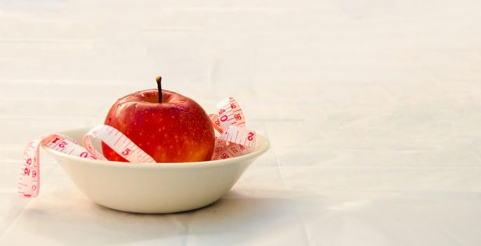 red apple with measurig tape, weigh loss concept, white background