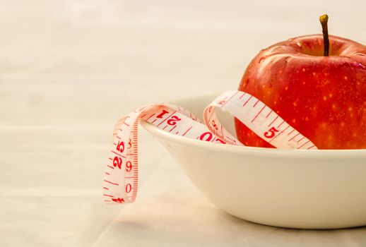 red apple with measurig tape, weigh loss concept, white background