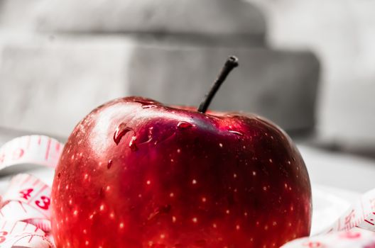 red apple with measurig tape, weigh loss concept, white background red tinting