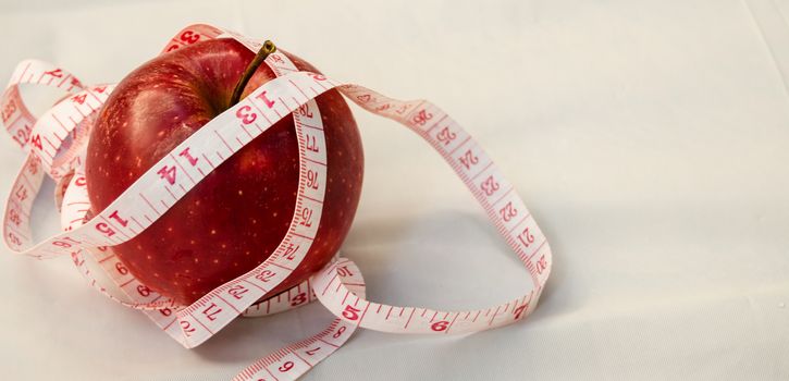 red apple with measurig tape, weigh loss concept, white background