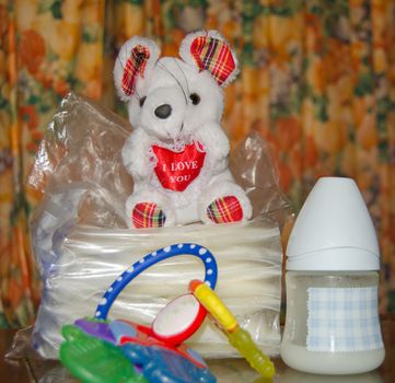 baby bottle with fresh expresed milk, frozen breastmilk in storage bags and soft toy mouse, breasfeeding concept