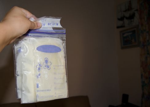 woman hand holding frozen breast milk in storage bags, breastfeeding concept