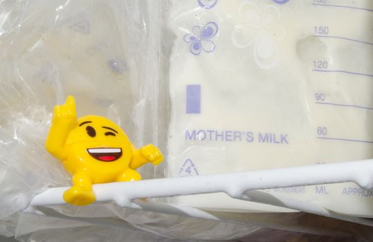 lot of frozzen breast milk in storage bags stored in the freezer and baby bottle with fresh expresed breastmilk, smille, breastfeeding concept