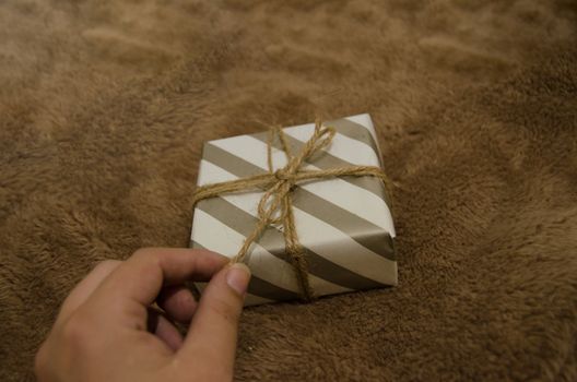 woman hand holding a gift box against brown background