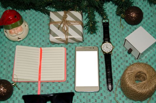 preparing for christmas at work concept flat lay with phone, notebook, gift, christmas ornaments, watch