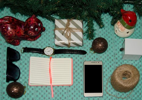 preparing for christmas at work concept flat lay with phone, notebook, gift, christmas ornaments, watch