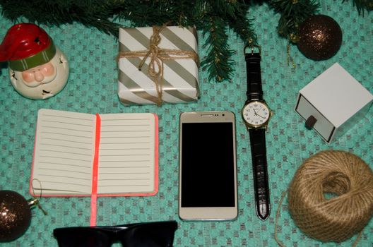 preparing for christmas at work concept flat lay with phone, notebook, gift, christmas ornaments, watch