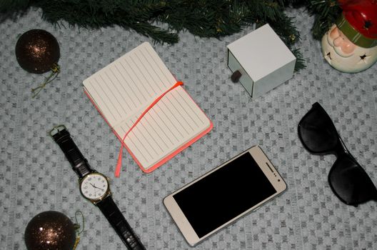 preparing for christmas at work concept flat lay with phone, notebook, gift, christmas ornaments, watch