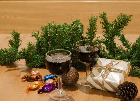 Two wine glasses on wooden table with gift box and christmas ornaments, new year or christmas concept