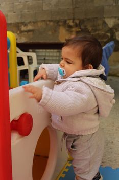 Baby boy playing with plastick house slide for toddlers