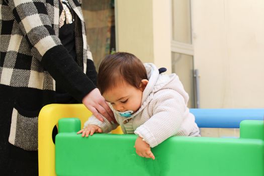 Mother holding Baby boy on plastick slide house