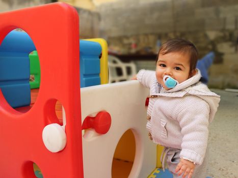 Baby boy playing with plastick house slide for toddlers