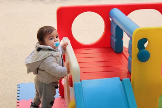 Baby boy playing with plastick house slide for toddlers