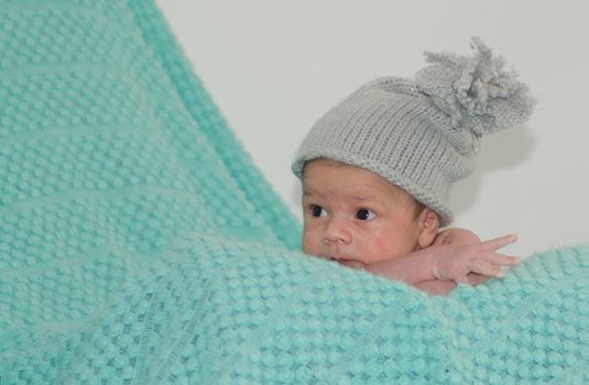 4 weeks old newborn baby boy with gray hat on green blanket copy space