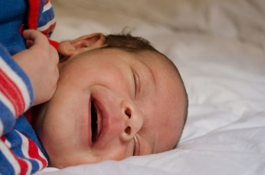 two weeks old newborn baby boy smilin while sleeping on white quilt, very cute smile