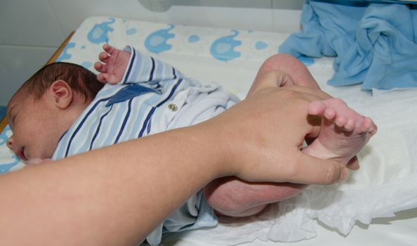 mother hand changing newborn baby on baby changer, relaxed baby