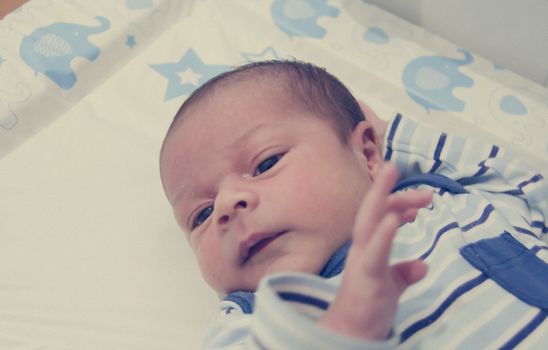 two weeks old newborn baby boy sleeping on white sheet, close up