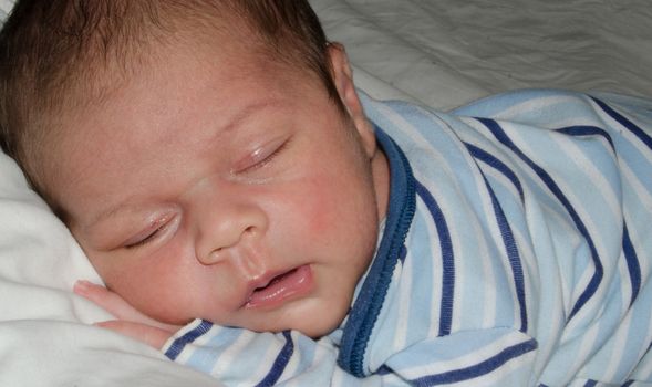 two weeks old newborn baby boy smilleing while sleeping close up